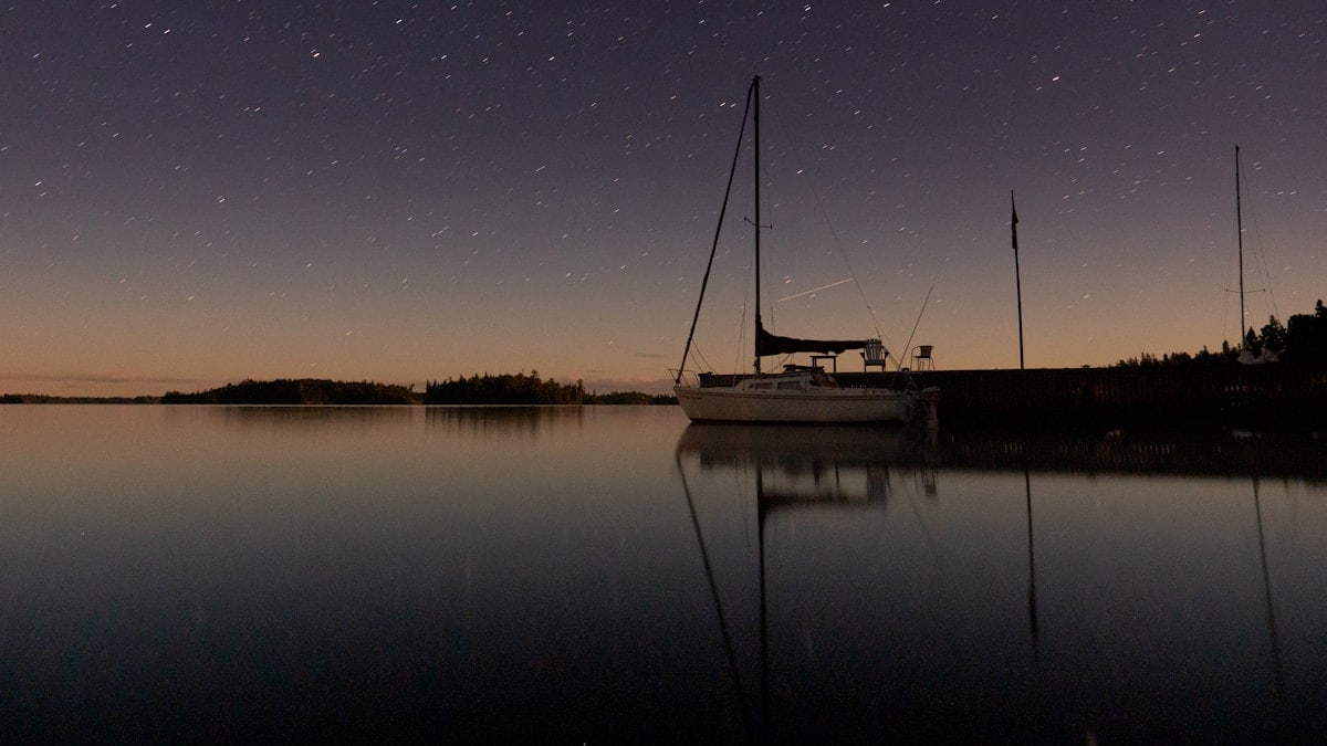 white boat on calm water under starry night