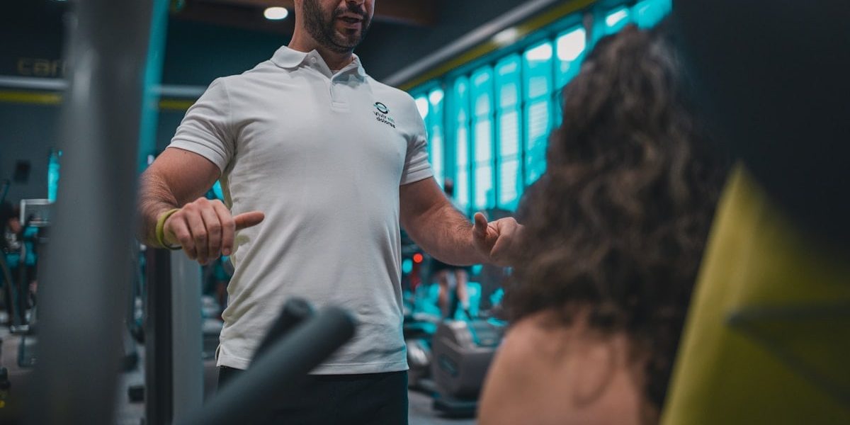 Sesión de entrenamiento en el gimnasio con un entrenador personal, enfocada en el rendimiento y el bienestar físico.